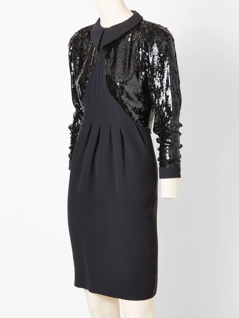 Geoffrey Beene, black silk crepe cocktail dress, having a tromp l'oiel, bollero of sequins, which include the sleeves , upper back and partial front. small pointed crepe collar finishes the look. Stitched down pleats cascade form the neck iine