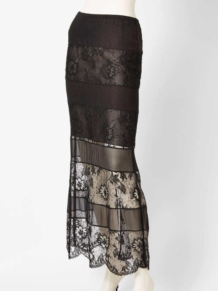 Chanel, black skirt in silk georgette with horizontal bands of fine lace mixed with a touch of lurex. Middle of the skirt has pin tuck detail on each tier. Lined just above the knee, and transparent from the knee down.
