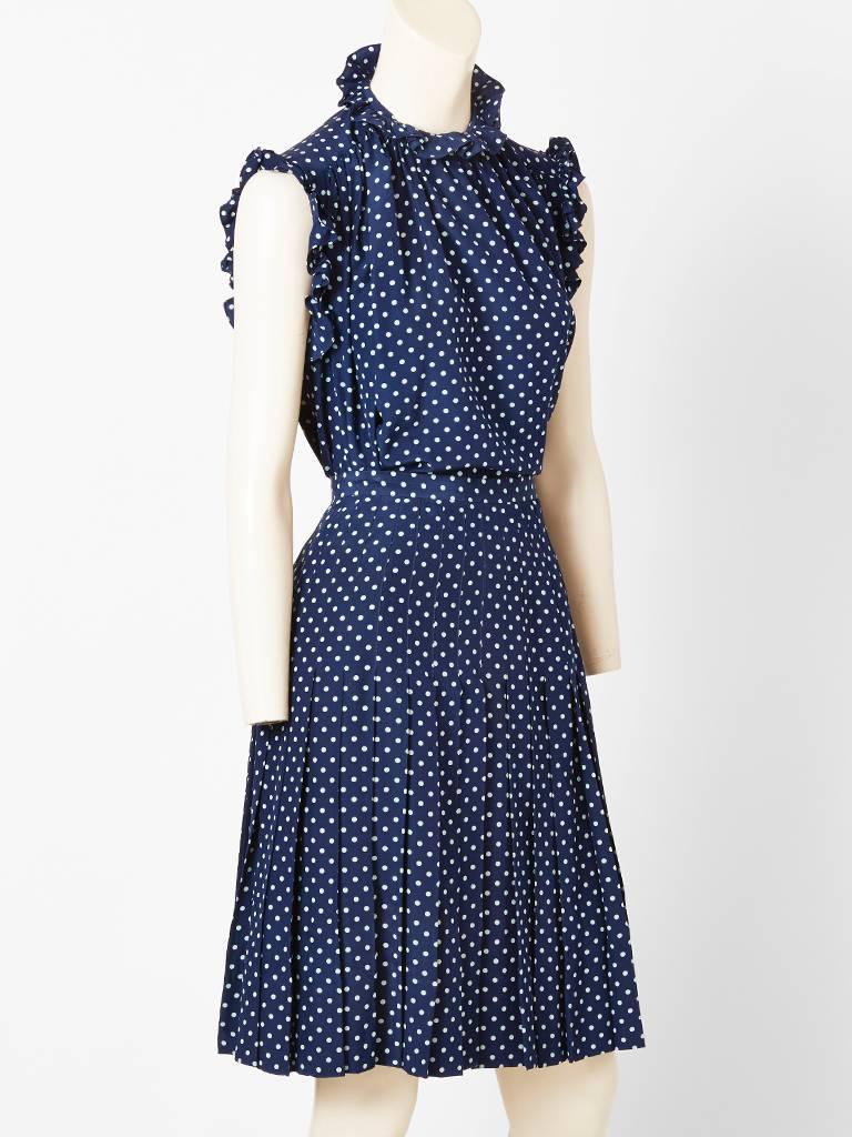 Chanel, navy and white, silk, polka dot top and skirt.
Blouse is sleeveless, having a ruffle neck and armhole, with gathering at the shoulders. Skirt is pleated with stitched down pleats at the waist to the hip.
The triangle ruffle scarf can be