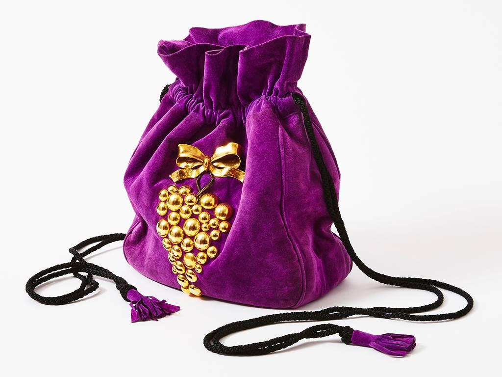 Yves Saint Laurent, purple suede, soft body, drawstring bag, embellished with gold tone, metal sculpted grapes and a bow. Black, corded drawstring having purple suede, tassels at the ends.