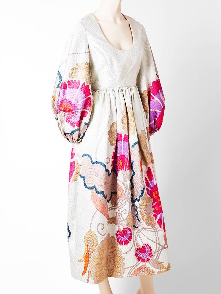 Bill Blass, floral patterned, brocade, scoop neck maxi dress having a empire waist, and full sleeves. Background fabric is in a shade of pearl grey with an 
Asian inspired floral motif.
