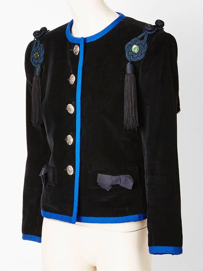 Yves Saint Laurent, box, cut, collarless,  black, corduroy jacket, embellished with silver tone textured buttons, corded, passementerie, and tassels placed at the shoulders, and gross grain bows on the flap pockets. Edged in a cobalt blue wool trim.