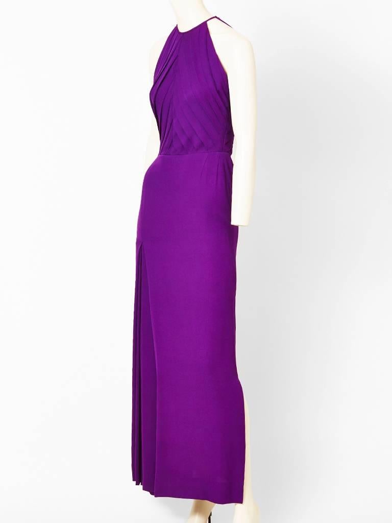 Galanos, purple, silk, crepe halter neck, evening gown with diagonally placed, 
pleating detail on the bodice. Skirt of gown has a deep inverted pleat on left side
to allow for movement. Simple and elegant. Side slit to the right.