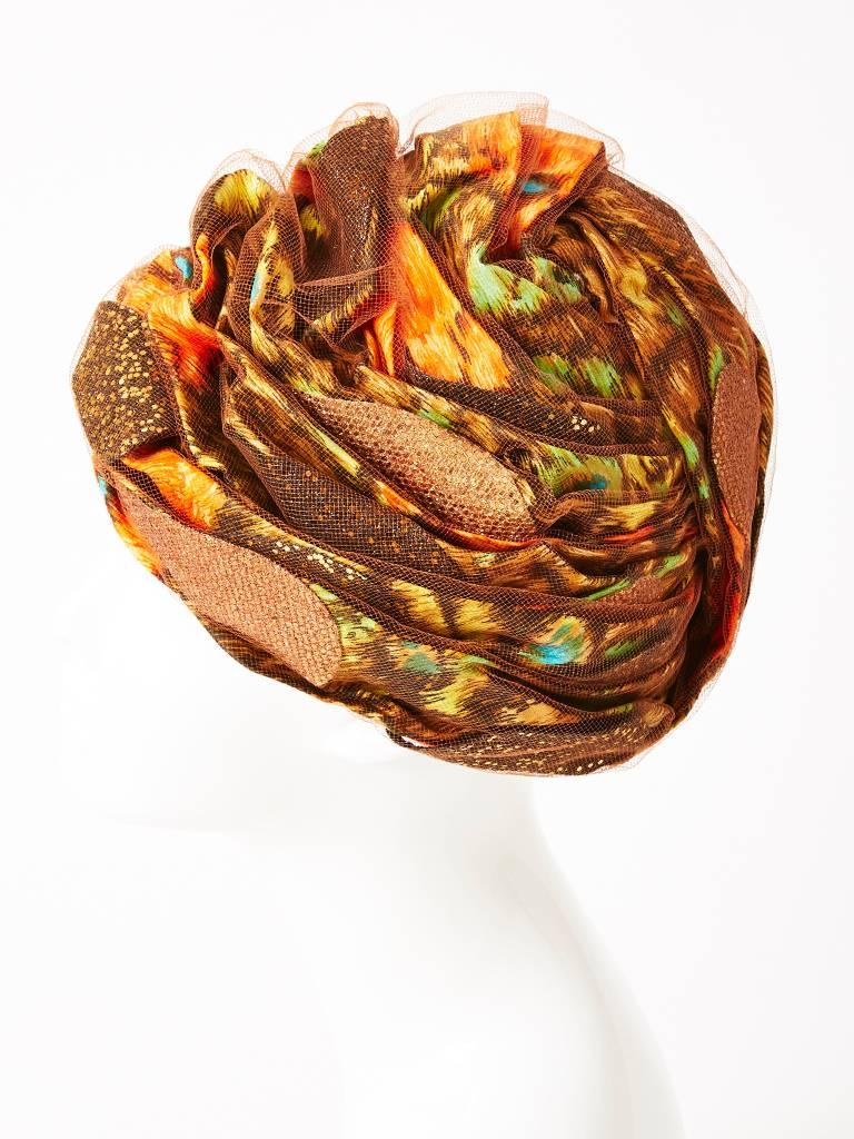 Christian Dior Chapeaux, patterned,  multi-color peacock printed Turban covered in tulle with tear drop shaped bronze glittered appliques.
