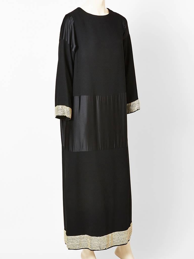 Norman Norell, black satin and wool crepe, long sleeve, chemise style, evening dress. Simple and elegant silhouette,having long sleeves, jewel neckline with a 
wool crepe bodice, then satin starting at the hip and ending above the thigh, then wool