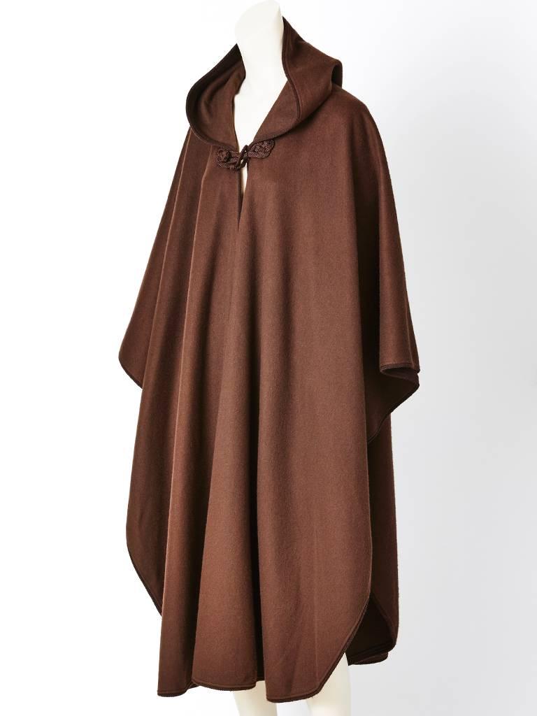 Yves Saint Laurent, Moroccan inspired cape in a warm brown shade, having a hood and passementerie, trim and detail closure at the neck. Large tassel attached at the point of the hood.