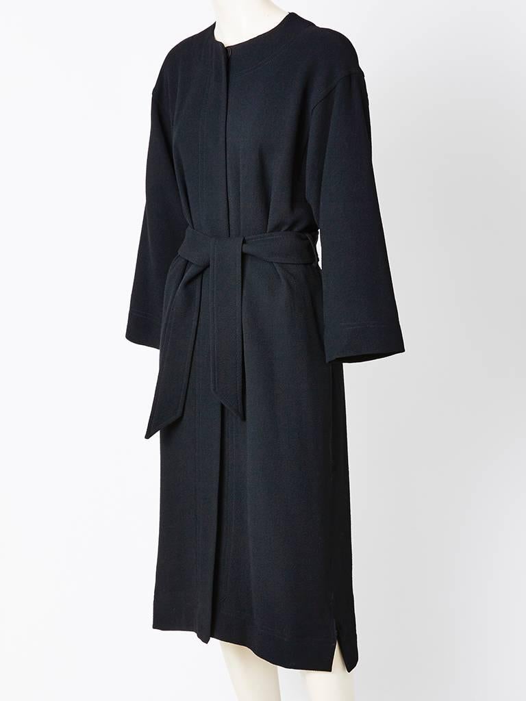 Jean Muir, black, wool crepe, belted coat/dress.. Simple, jewel, round neckline, semi wide, kimono-like sleeves, straight silhouette that gathers when belted with hidden button closures.