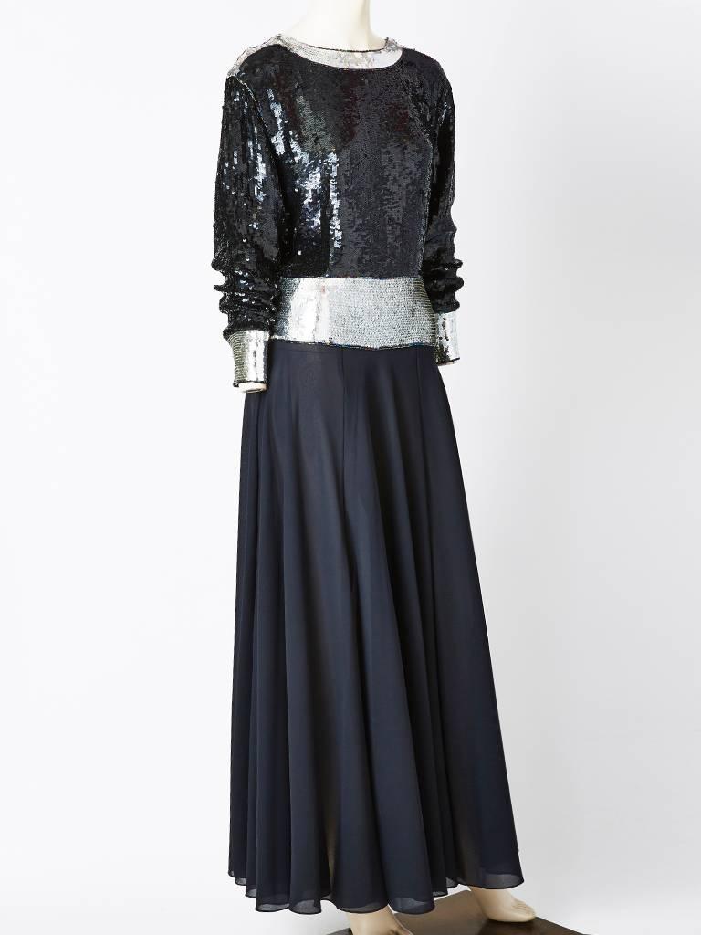 Yves Saint Laurent gown, having a bodice, that is encrusted in black and silver 
paiettes. Rounded neckline, has a band of silver detail as well as the cuffs and waist. The waist is cut low,and can blouson for a softer look. Raglan sleeves narrow