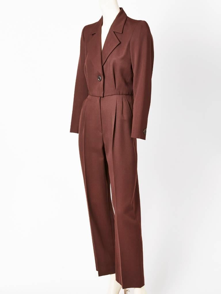 Yves Saint Lauren, chocolate brown, wool gaberdine, jumpsuit having a bodice with lapels, looking like s suit with a single button closure. Pant is a men's trouser style with hip pleats. Front hidden zipper in the pants.