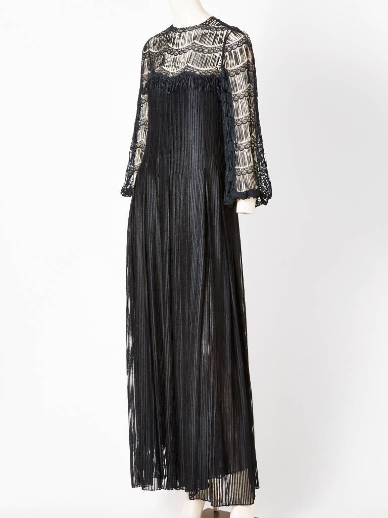 James Galanos gown, having a neckline and sleeve with open work and lace detail. Bodice is semi fitted with the skirt having box pleats that start at the hem and extends to the hem. Neckline and sleeves expose the skin, where the bodice and hem are