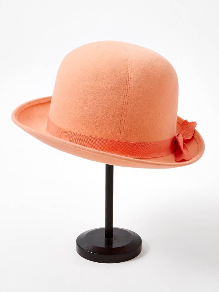 Adolfo, wool felt, peach tone fedora, having a rounded crown and matching gross grain ribbon with a bow embellishment at the base of the crown.