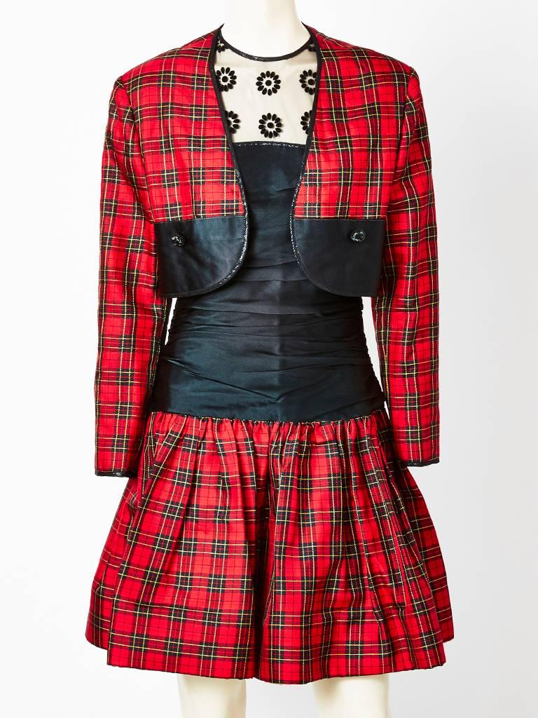 Geoffrey Beene, tartan, taffeta and tulle cocktail dress having a matching bolero jacket. Dress is composed of a tulle neck and shoulder with a flocking embellishment. The bodice and hips are a fitted ruched taffeta. From the upper thigh, down to