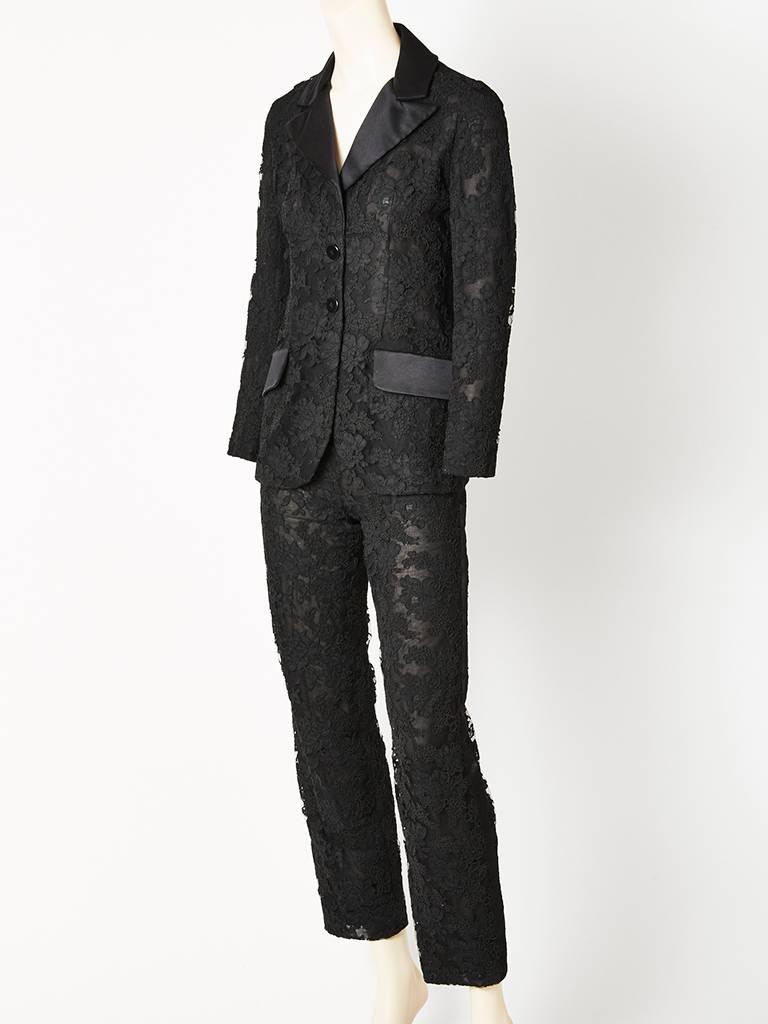 Bill Blass, black, lace, tuxedo pant suit, having a fitted jacket with satin lapels and flap hip pockets. Pants are slim with a back zipper closure. Jacket and pants are lined in silk chiffon. C. 1980's