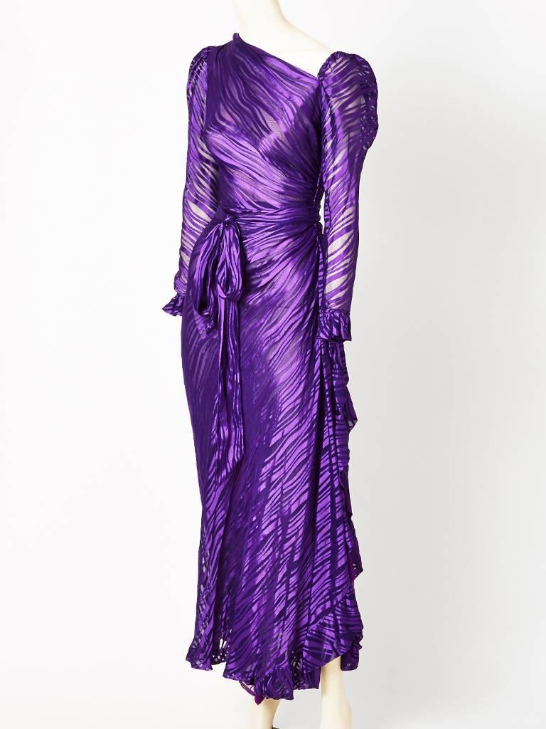 Yves Saint Laurent, purple, bias cut, asymmetrical neckline, long sleeve gown, having a self belt that ties at the waist.

