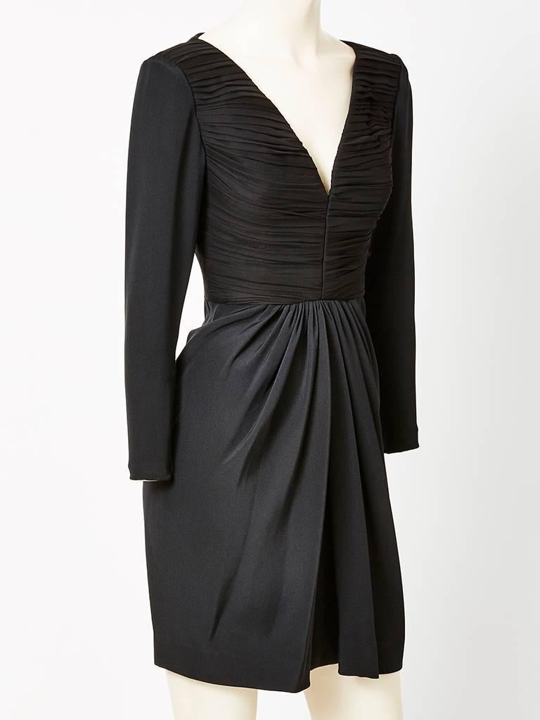 James Galanos, 3 ply, silk crepe,  cocktail dress, having long sleeves with a deep v neck at the center. Bodice is very fitted with signature, Galanos horizontal ruching . Skirt is bias with gathered soft draping that starts at the waist and flows