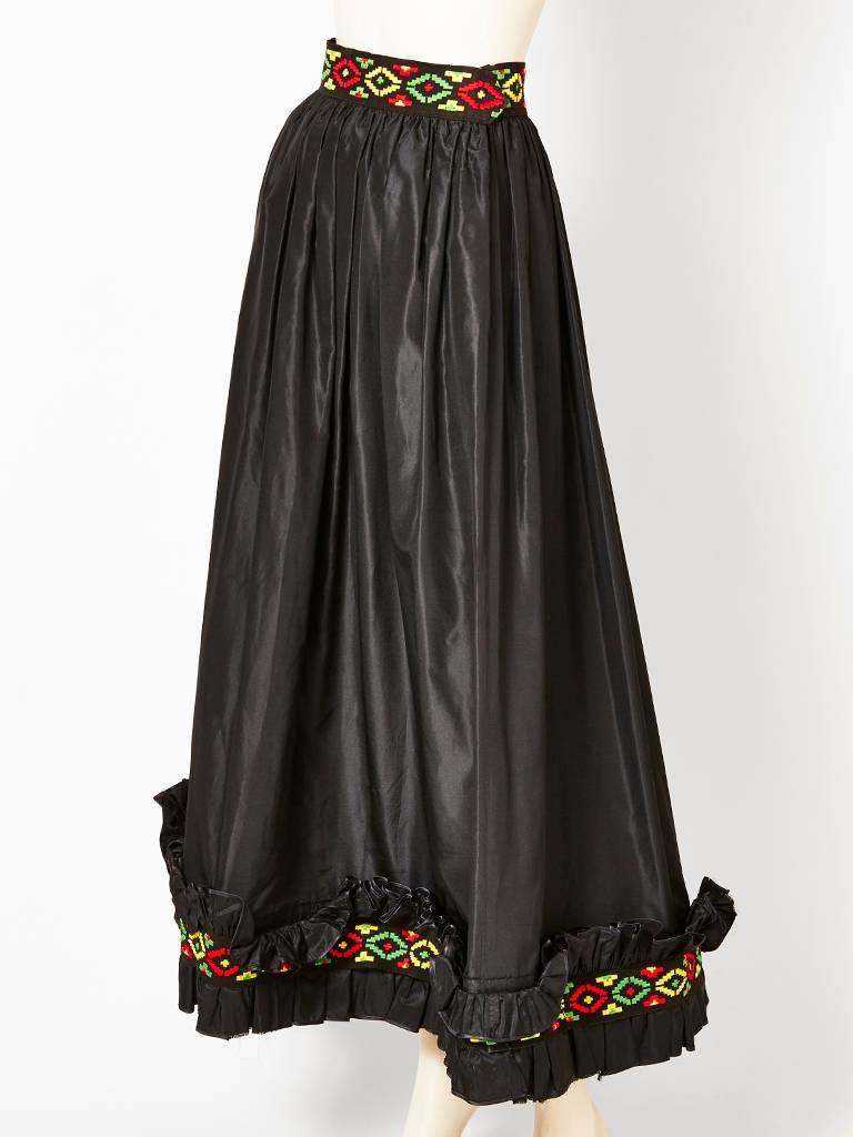 Yves Saint Laurent, black taffeta, peasant style, skirt, gathered at the waist with ruffle detail at the hem. At the waist band and hem there is a multicolored, embroidered band of 