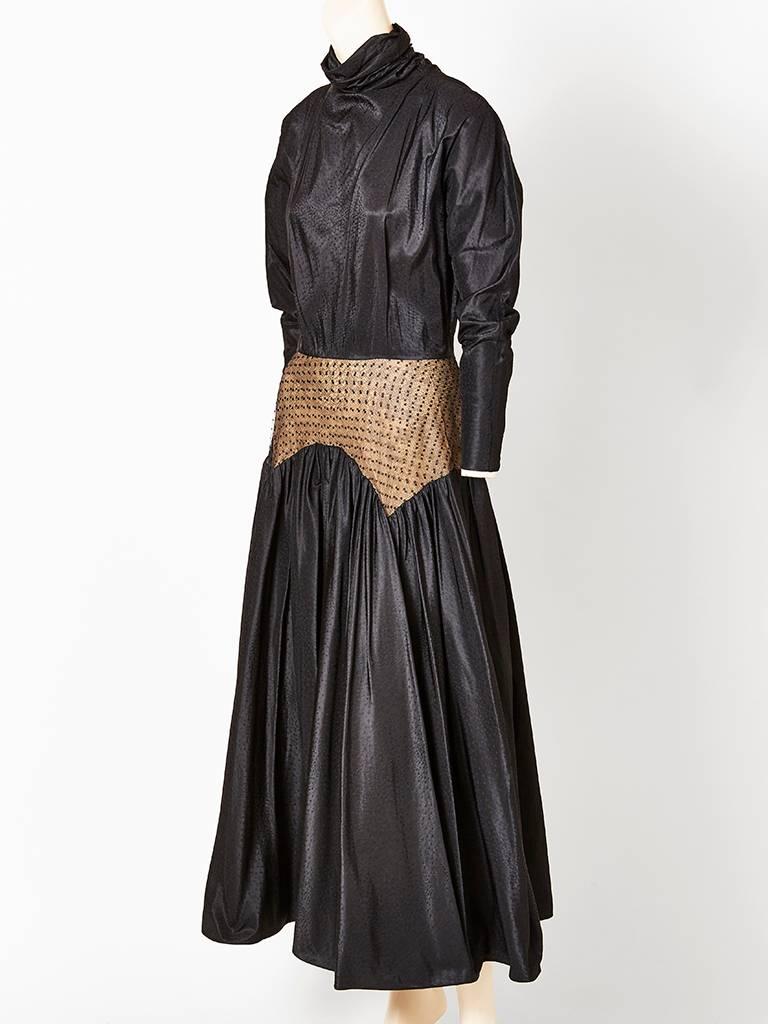Geoffrey Beene, black silk jacquard dress, having a soft funnel neck that is ruched at the sides. Sleeves are raglan, that get narrow at the wrist.There is a point d'esprit pannel  that sits at the waist and hip over a nude tone taffeta.
Skirt of