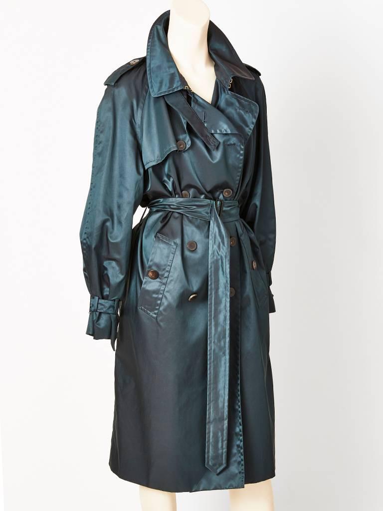 Yves Saint Laurent, classic, belted, trench, in a rich, petrol green tone, having  a shimmery, satin finish.