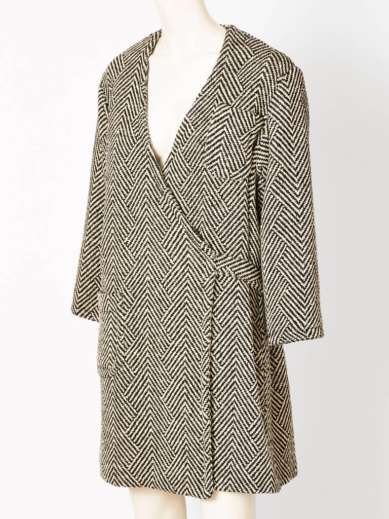Rudi Gernreich, black and white herringbone tweed wrap coat , having a  V neckline, single pocket, and wrap closure that fastens in the back. C. 1960's
( Label Missing).