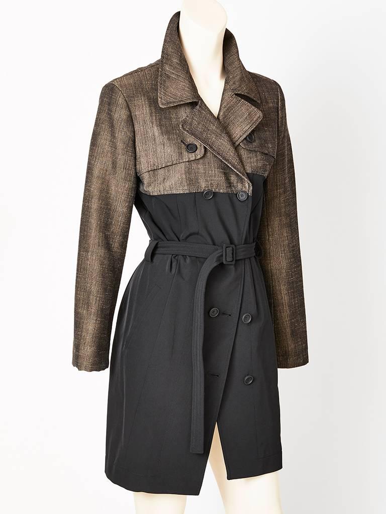 Nicholas Ghesquiere, for Balenciaga color block, double breasted trench,
having a taupe, textured linen type fabric upper bodice. The balance of the coat is a black synthetic stretch that fits close to the body. The closure is asymmetric. 
