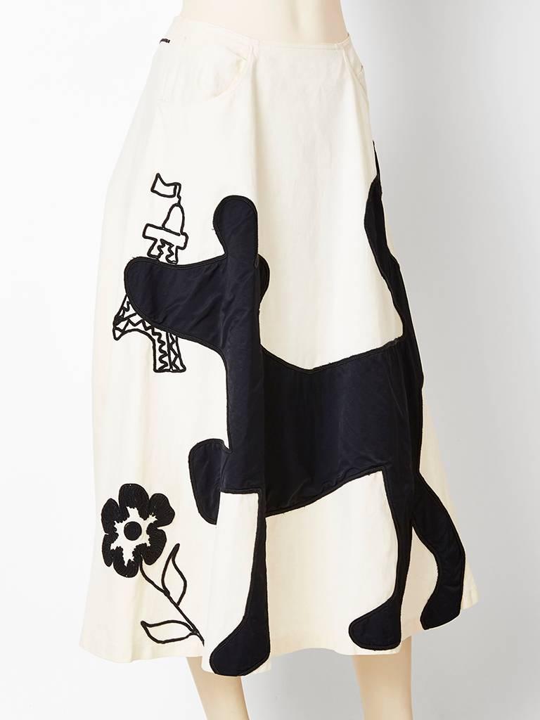 Jean Charles de Castelbajac, whimsical midi, skirt in an ivory cotton canvas having black appiques and embroidery depicting a dog, Eiffel tower and flowers. Skirt has a full a line shape with hip pockets. 