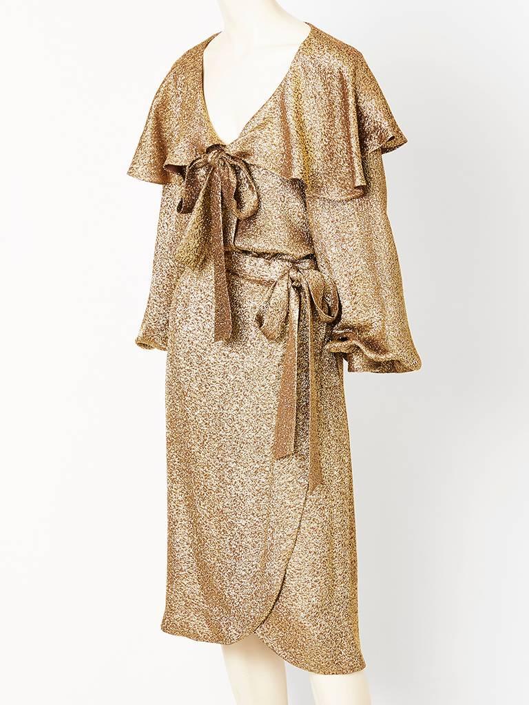 Adolfo, evening, gold lamé skirt and blouse ensemble. Blouse has a grand;; Bertha flounced collar with an open neckline, having a generous center bow.
Wrap skirt is of the same fabric as top and ties at the side with another generous bow.
