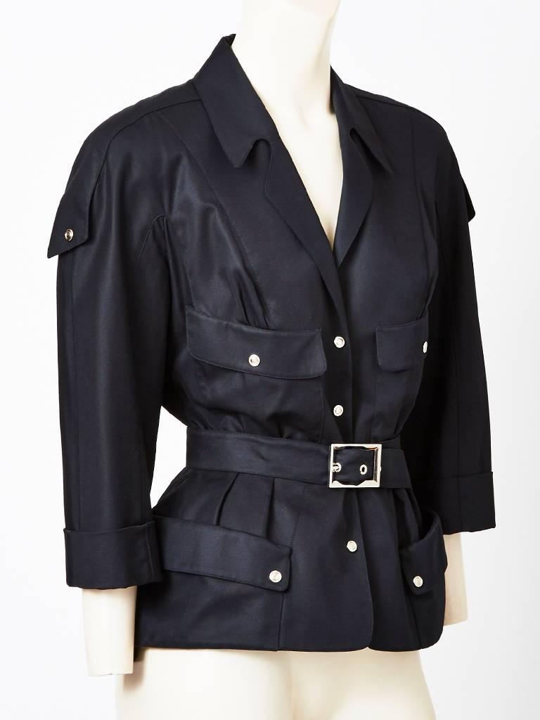 Thierry Muglar, black cotton gaberdine, belted, safari inspired jacket. 
The silhouette is fitted with a sculptural emphasis on the hips that stand away a bit from the body. The button closures are chrome like including the belt buckle.
There are