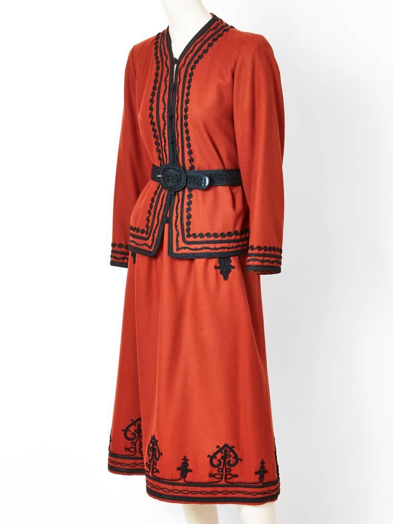 Yves Saint Laurent, Rive Gauche, rust tone, wool, belted jacket and skirt ensemble, having black passementerie detail on the skirt and jacket. Jacket has a hook and eye closure. From the  Russian Cossack collection, late 70's.