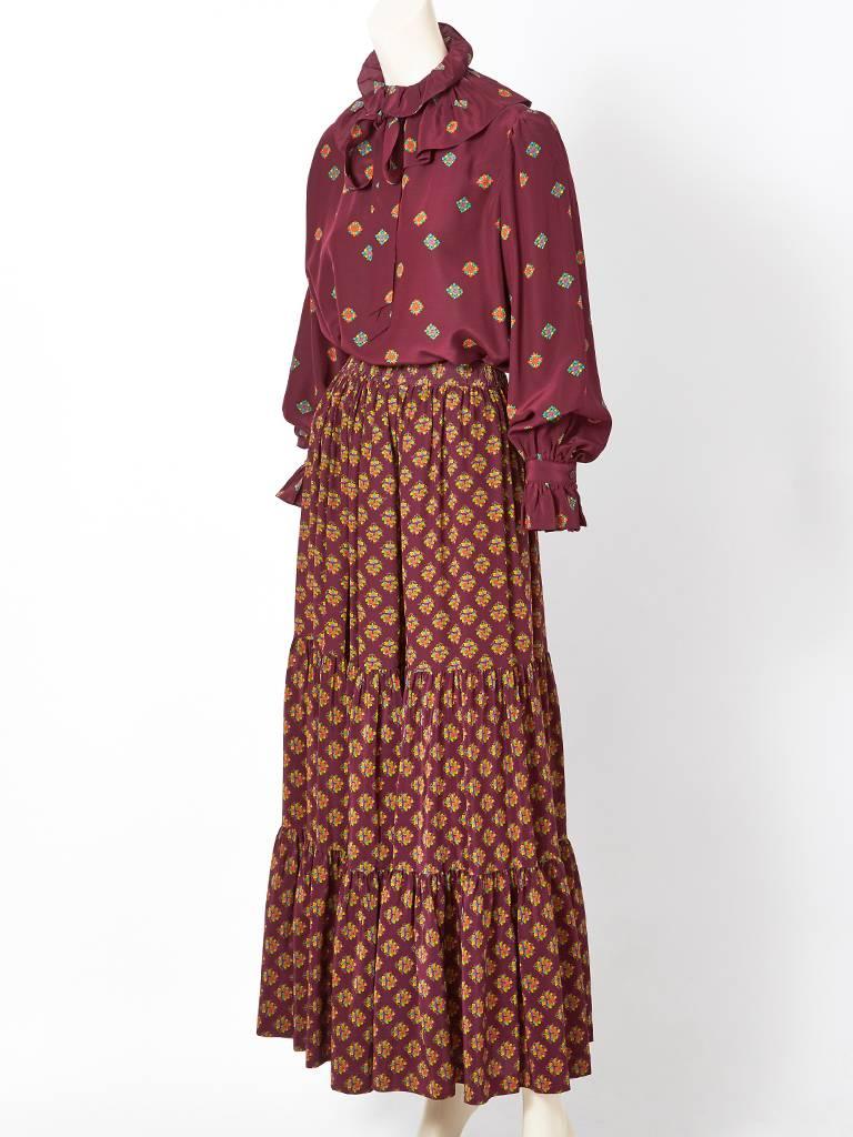 Yves Saint Laurent, silk, foulard print, blouse and skirt maxi ensemble from the Russian Collection, late 70's. Skirt is tiered with an elastic waist. Top has a ruffled collar with a tie and a tightly cuffed sleeve. Rich burgundy color with mixed