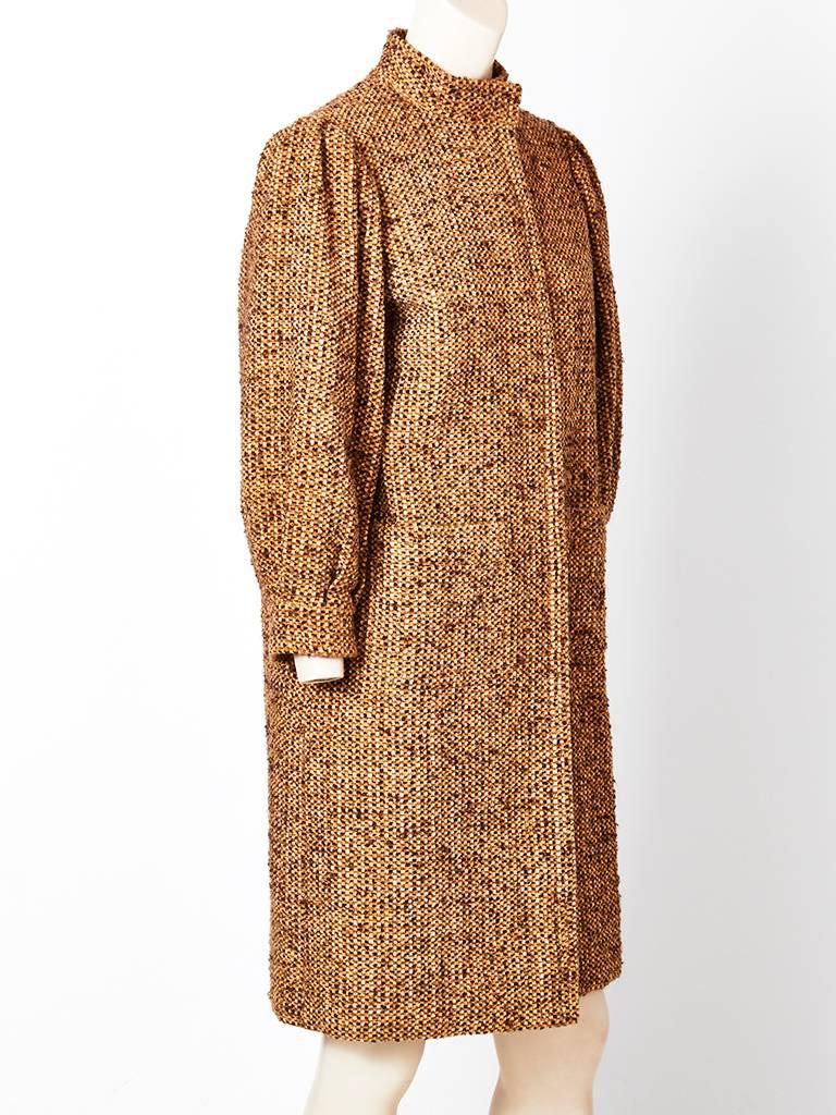 Galanos, mustard and brown tweed, wool coat having a mandarin collar, blouson sleeves with gathering at the shoulder, hidden button closures, and patch pockets. Coat has a slim silhouette.