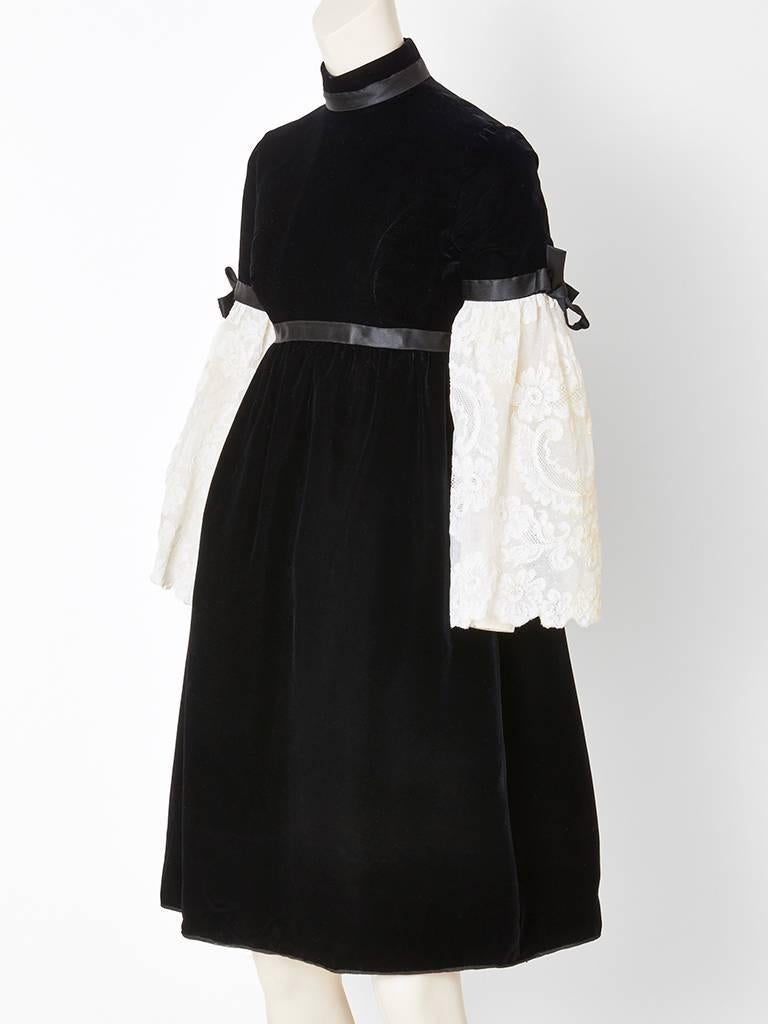 Geoffrey Beene, black velvet empire  waist, baby doll style dress, having a high neck satin collar and a bell sleeve treatment. There is a velvet sleeve that ends at the elbow, then a full white lace sleeve that extends from the velvet and ends
