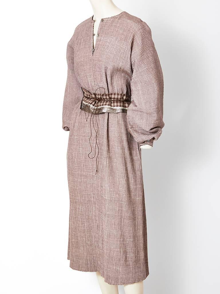 Geoffrey Beene taupe tone, over sized, crinkled wool, belted caftan/day dress C. late 70's.
Voluminous, raglan sleeve that cuff at the wrist and an obi inspired patchwork wrap belt made from a combination of fabrics ( including a metallic) and