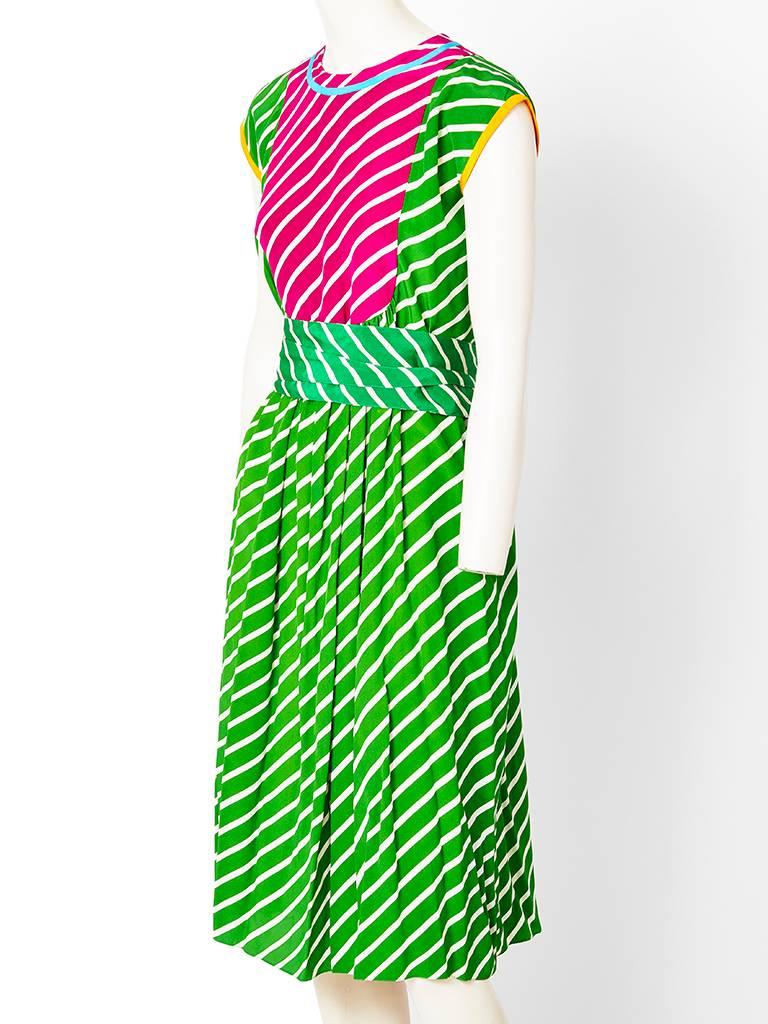 Geoffrey Beene , diagonally striped, silk dress with an attached belt.  Dress has cap sleeve, jewel neckline, with an inserted bib at the bodice in a fuchsia and white stripe. There is a robins egg blue piping  along the jeweled neckline and the