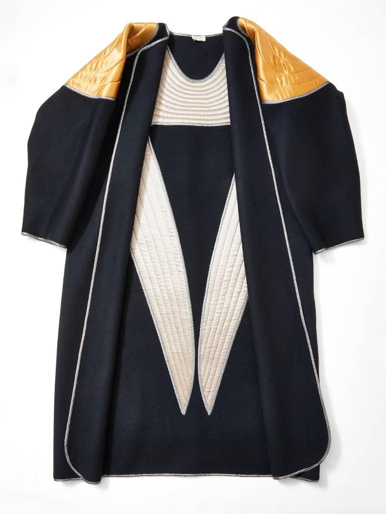 Geoffrey Beene, double face wool, coat, having a gold satin quilted applique detail in a geometric pattern on the back and shoulders. Silver Lamé piping along the edges of the garment. No closures .
C. 1983. 