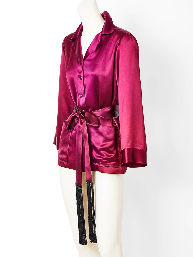 Yves Saint Laurent, cranberry tone, satin, men's style smoking jacket, having a notched collar, front button closure, patch pockets and a belt with long black tassels.