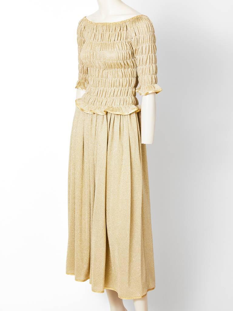 Geoffrey Beene, gold lurex knit ensemble, having an elastic puckering mid elbow sleeved, boat neck top and a gathered skirt. Top and skirt are edged in a gold lamé piping detail. C. late 70's.