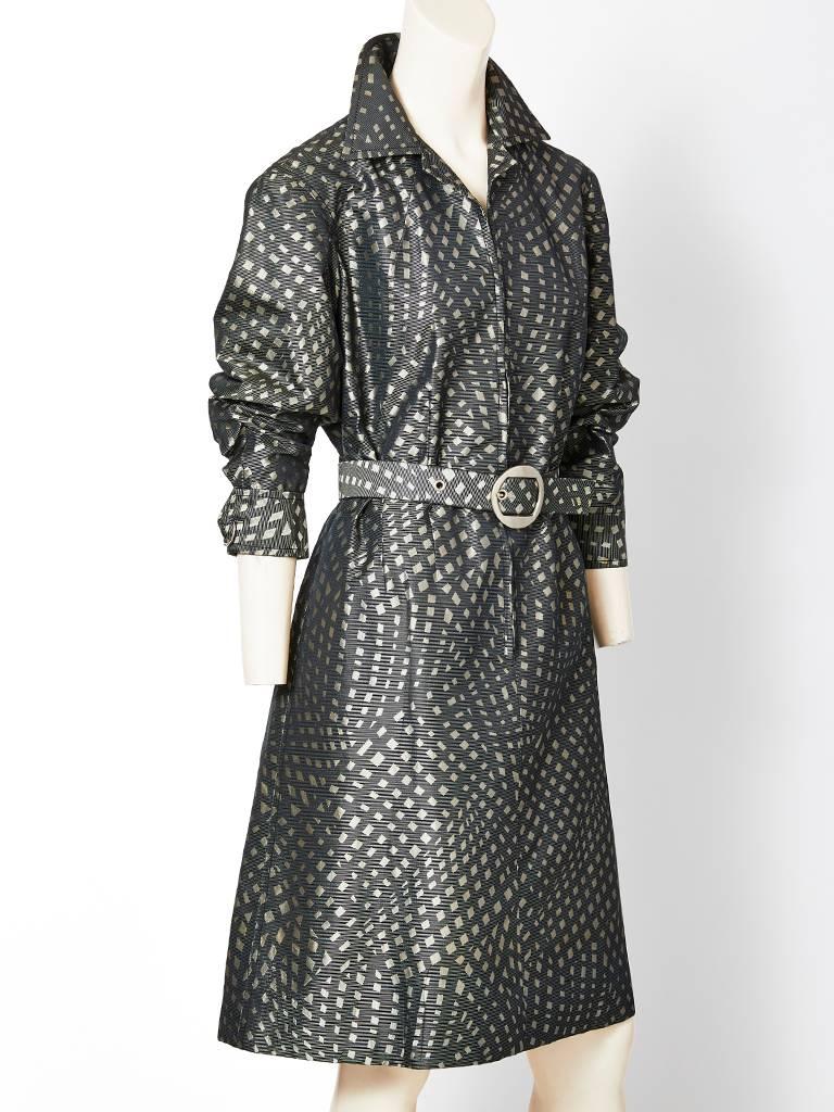 Galanos, silk weave, geometric pattern, belted shirtwaist, dress, in charcoal with a metallic geometric pattern. The dress has a stand up collar and a hidden front zipper closure . The tent like shape becomes flattering when belted with its self