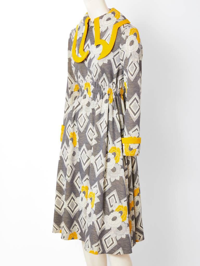 Ronald Amey, wool knit,  grey and mustard, patterned, day dress  having an asymmetric large cut out collar  trimmed  in a mustard tone. Back zipper closure with an elastic waist. C. 1970's.