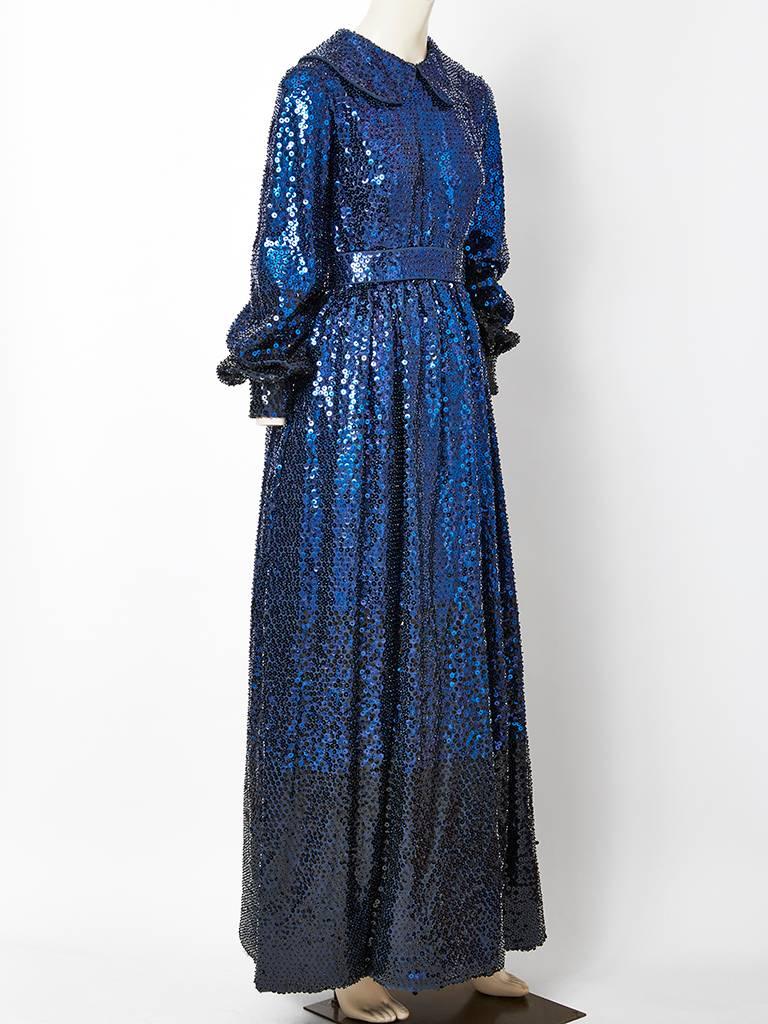 Donald Brooks, gown, encrusted with  sapphire blue sequins. Dress has a peter pan collar, long full sleeves that cuff at the wrist, sight gathering at the waist and a self belt that fastens at the back. The blue sequins, ombrés into black about 12