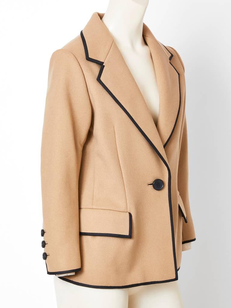 Norman Norell, camel tone, wool Blazer having black trim detail, a single button closure, and notched collar. Flap side pockets have black trim as well.
