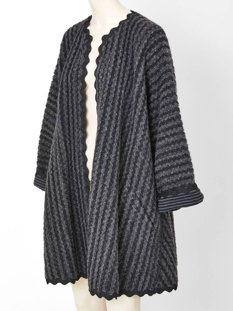 Geoffrey Beene, wool knit and mohair ribbed, grey kimono style, swing coat having a grey and black striped interior and black large ric rac trim. 