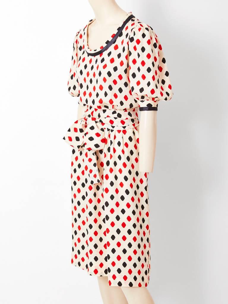 Yves Saint Laurent, Rive Gauche, ivory silk, having a black and red diamond pattern day dress. Dress details, include a U neckline, having black piping and full sleeves that end at the elbows. There is a generous self belt that be wrapped around the