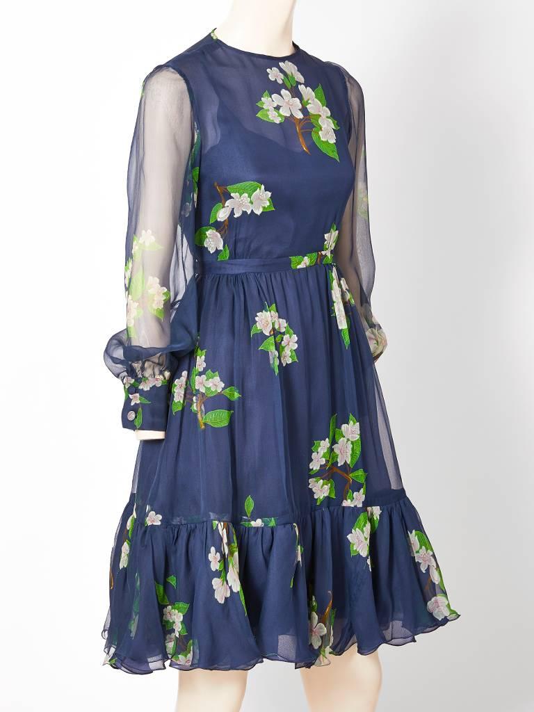 Valentino, navy organza, dress with a floral branch motif. Dress has a jeweled neckline with long sheer sleeves that cuff at the wrist. Skirt is full and gathered having a ruffled flounce at the hem. Signature, Valentino femininity.