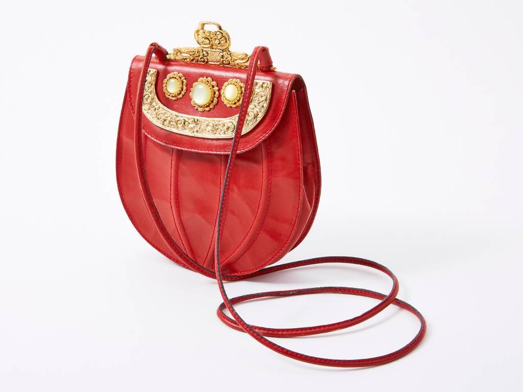 Ugo Correani, red leather half round small shoulder bag, having a a gold tone, baroque frame and clasp and a flap closure embellished with milky tone round stones and more gold baroque embellishments.
Raised curved stitch detail in the front.
