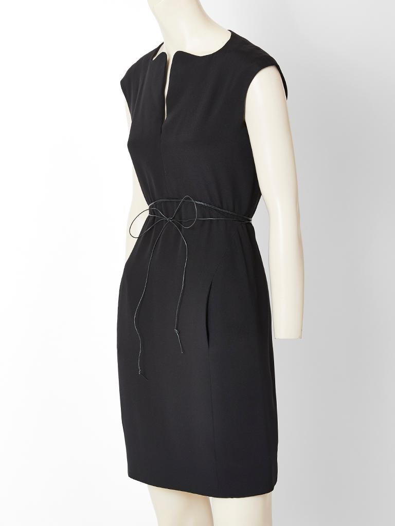 Geoffrey Beene, black, silk crepe dress, having cap sleeves and  a unique v neckline that curves symmetrically. Black, string, patent, accent belt wraps around the waist.