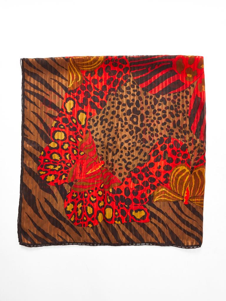 Yves Saint Laurent, Rive Gauche, large square, silk scarf, having a collage of mixed patterns of leopard, butterflies and tiger stripe. Brilliant shades of red orange, rust, and black.