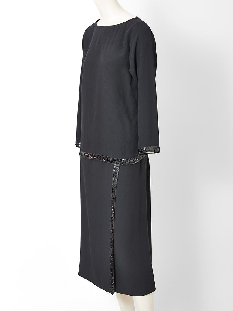 Yves Saint Laurent, Rive Gauche, viscose, satin back crepe, skirt and tunic ensemble. Tunic top has a bateau neck, long sleeves and a black sequined border at the hem and wrists. Wrap skirt, has front,  vertical sequin edging .