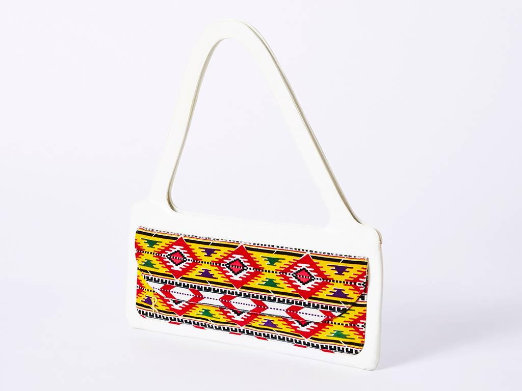 Roberta di Camerino, white leather, slim bag that can be worn over the shoulder or as a handbag. Unusually slim shpe with a front panel detail of a velvet ethnic inspired pattern in bright primary collars. Bag has a flap pocket on the outside front