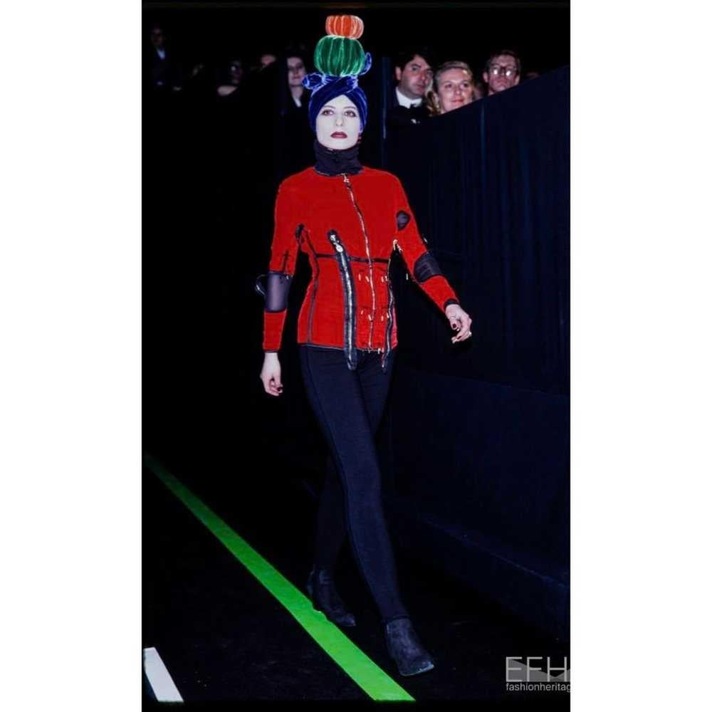 Cet ensemble deux pièces de la collection automne-hiver 1989 de JEAN PAUL GAULTIER est audacieux et audacieux. Il allie un design épuré à des éléments d'inspiration industrielle. Confectionné dans un luxueux velours noir, cet ensemble se compose