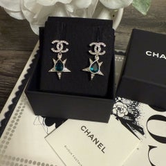Pendientes colgantes CHANEL de cristal plateado con la inicial CC y una estrella de gemas verdes